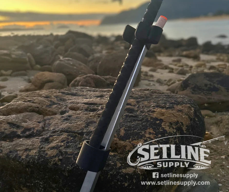 A beach spike holding a surfcasting rod on a rocky NZ beach at sunset