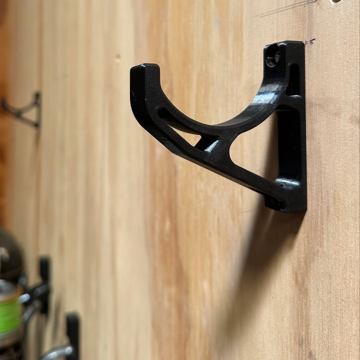Black metal bracket on a wooden surface with tools in the background